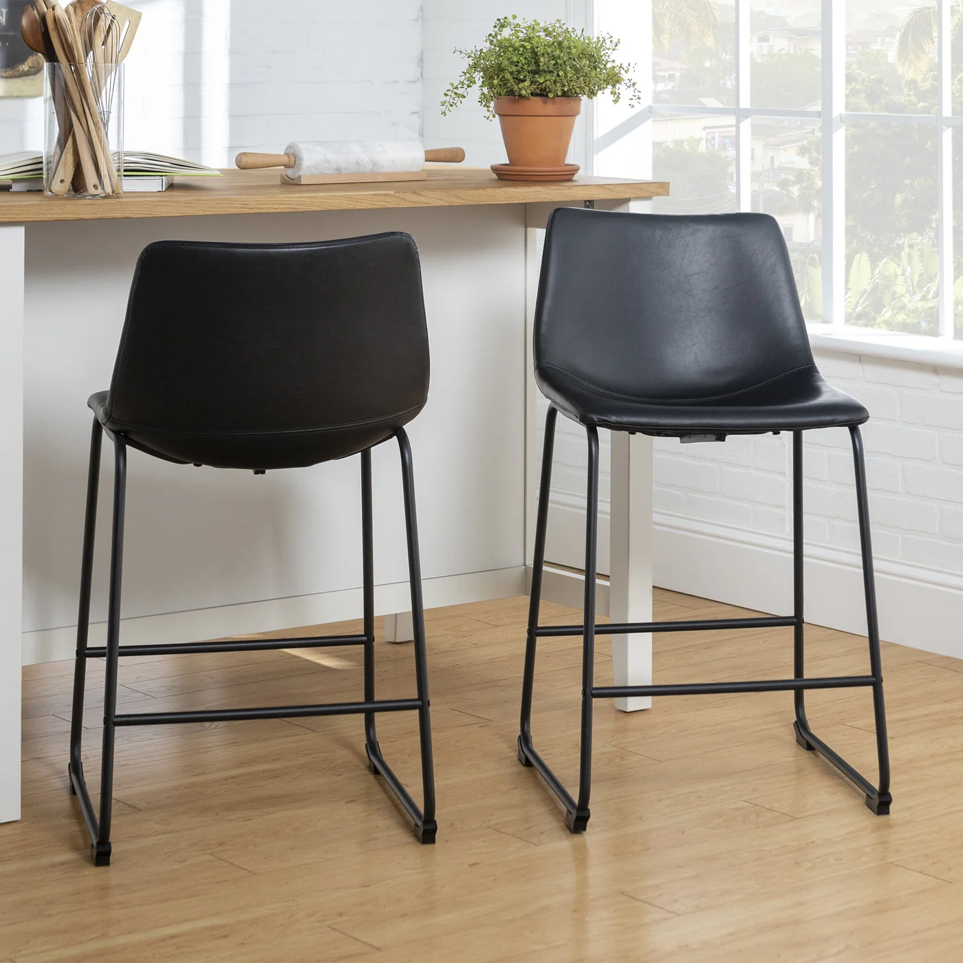 Two black bar stools in a room with a wooden table and window.